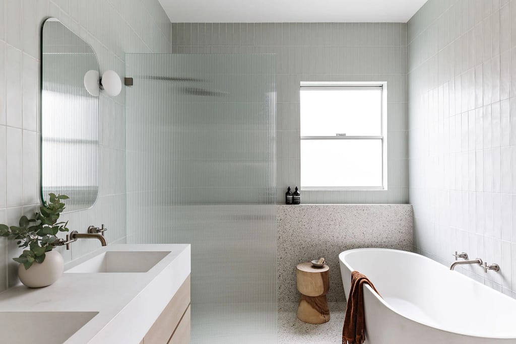 Contemporary Dundarave bathroom featuring a fluted glass shower screen, freestanding soaking tub, terrazzo wall accents, and vertical stack bond tile