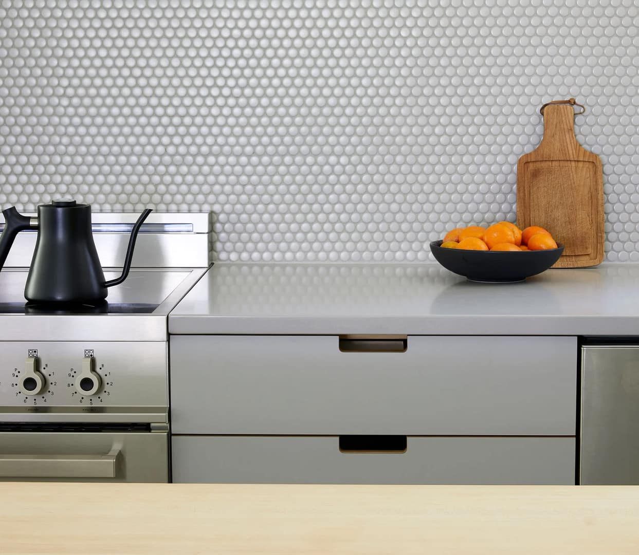 High-end laundry room renovation in Lougheed by Quay Construction featuring natural wood cabinetry, white stone countertops, and integrated side-by-side appliances.