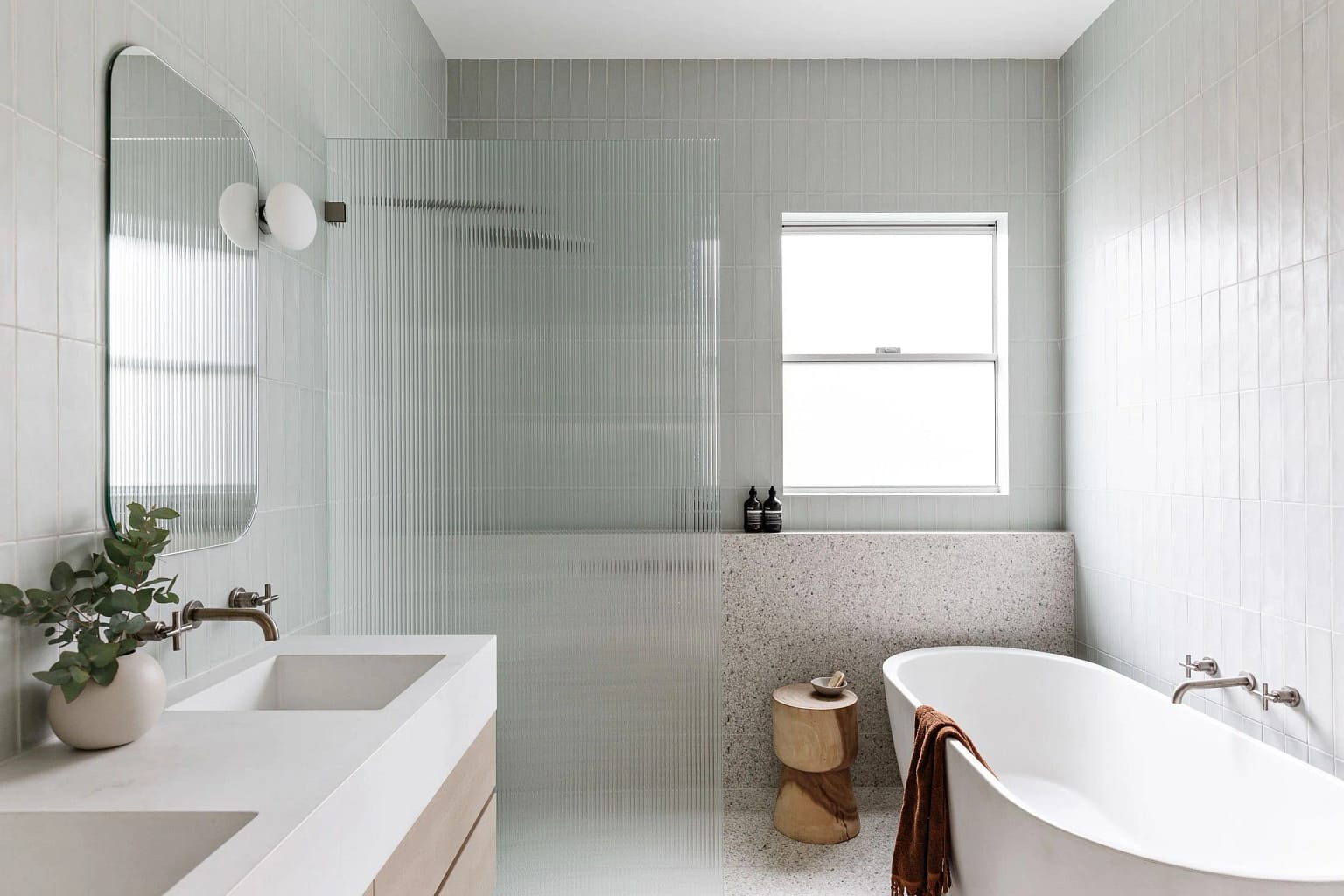 Luxury bathroom renovation in Burnaby featuring a freestanding soaking tub and fluted glass shower partition by Quay Construction.