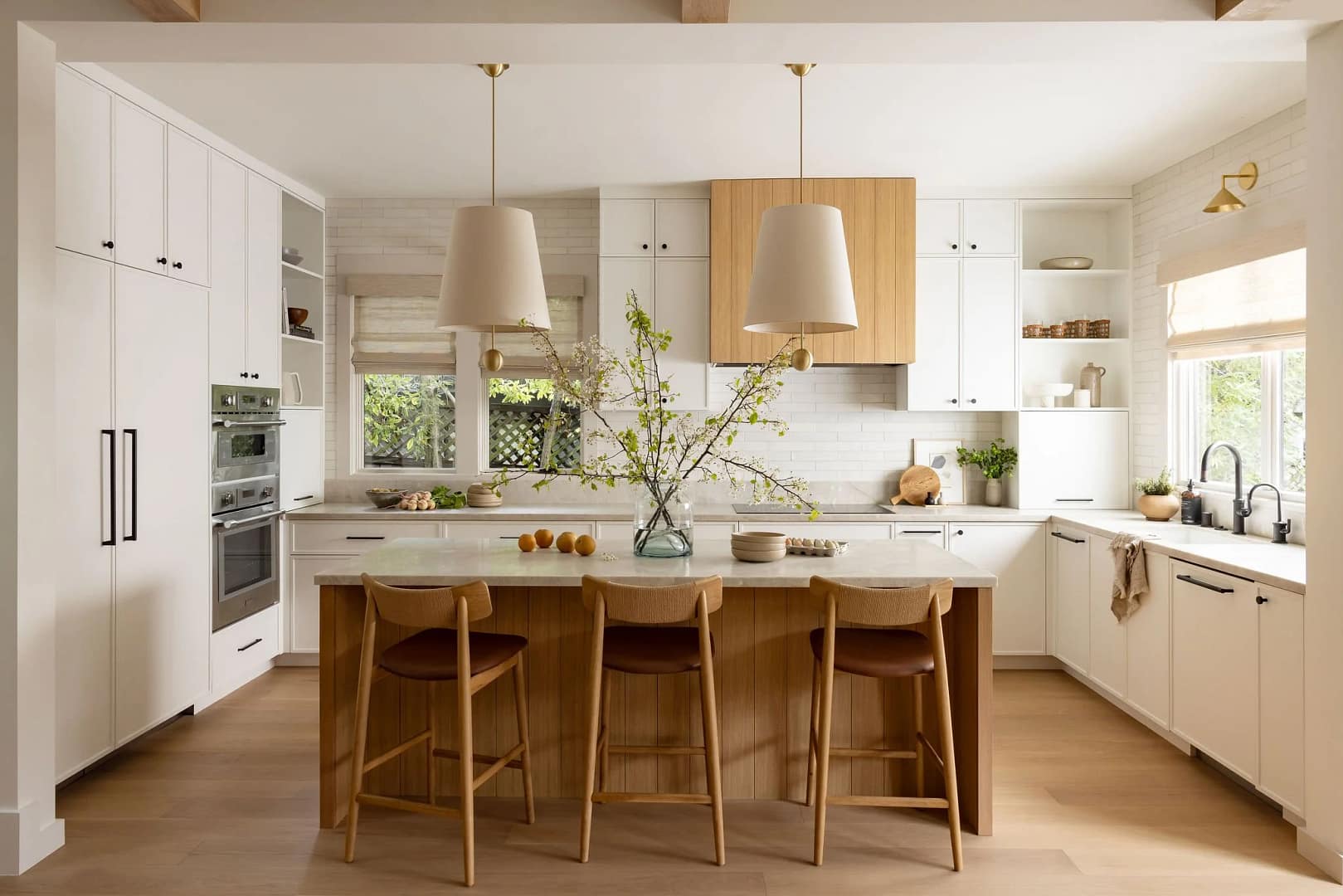 A luxury kitchen renovation in Langley by Quay Construction featuring white shaker cabinets, a natural oak island with leather barstools, and oversized cream pendant lights.