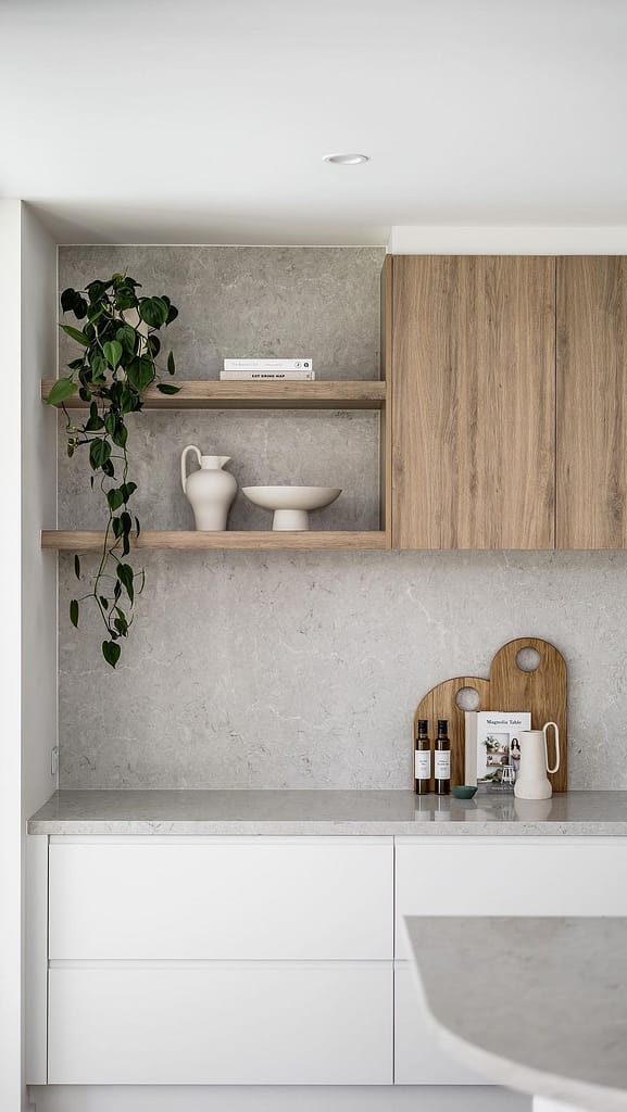 Close-up of a Coquitlam kitchen design featuring two-tone white and wood cabinetry, open shelving with trailing plants, and a full-height grey stone backsplash.
