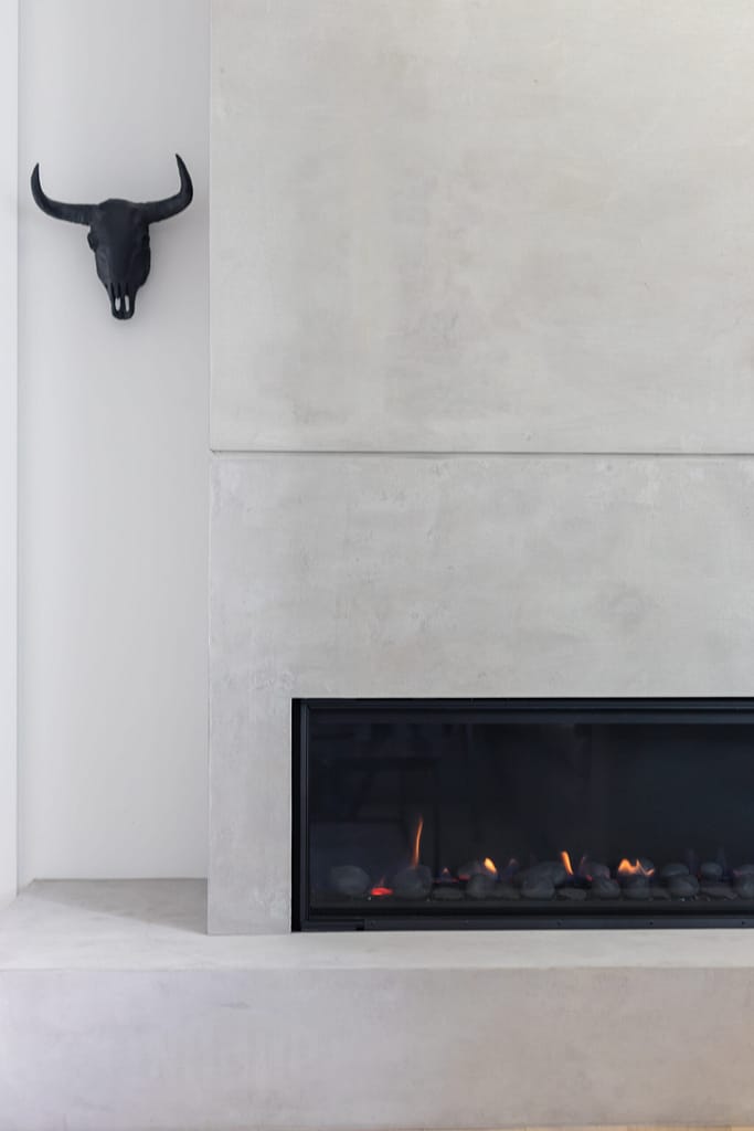 modern fireplace with concrete paneling and ox wall art