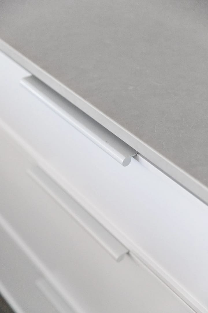 Detail of a modern kitchen remodel in Surrey BC by Quay Construction featuring a grey stone countertop and sleek white handleless cabinetry.