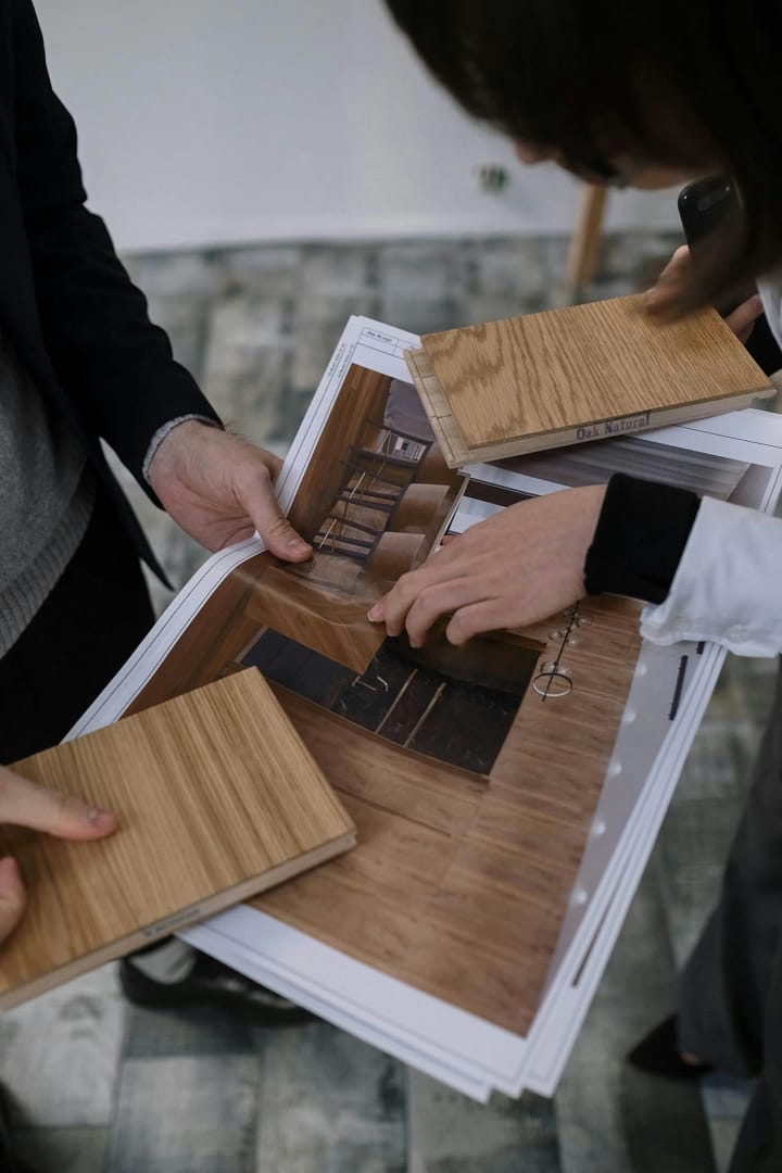 Quay Construction designers in North Vancouver comparing natural oak wood samples with architectural kitchen floor plans.