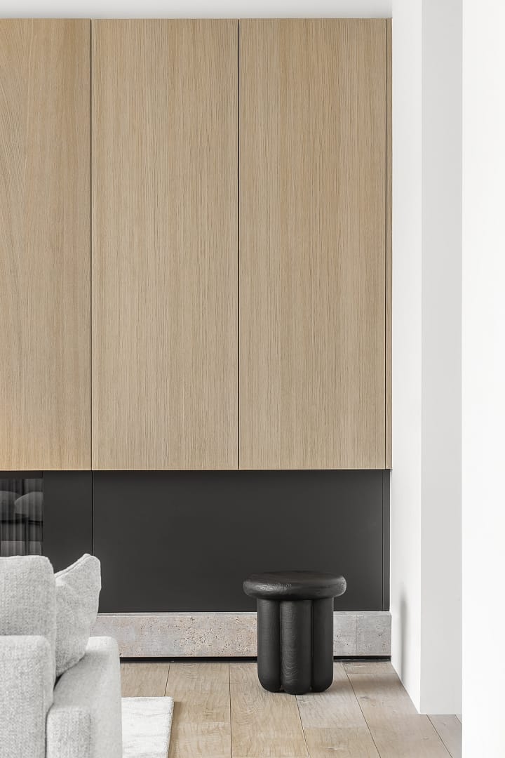 Modern home renovation in Edgemont Village by Quay Construction featuring minimalist oak wall paneling and a custom black fireplace surround.