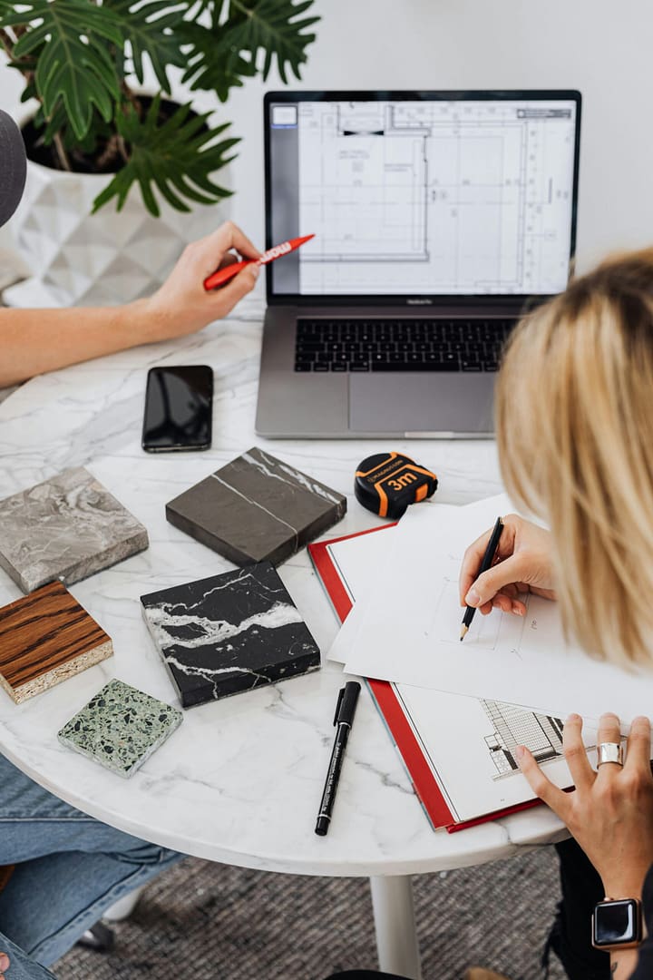 Designers reviewing marble samples and digital floor plans for a kitchen renovation Vancouver by QUAY Construction.