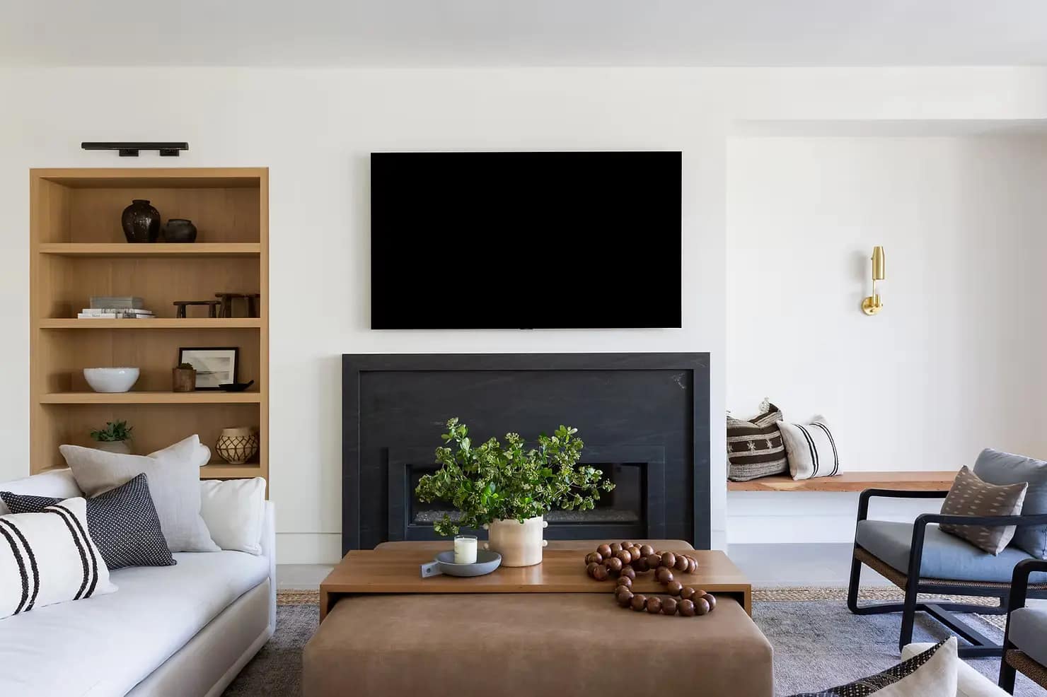 Modern living room home renovation in Surrey featuring a custom black fireplace, built-in oak shelving, and contemporary furniture by QUAY Construction.