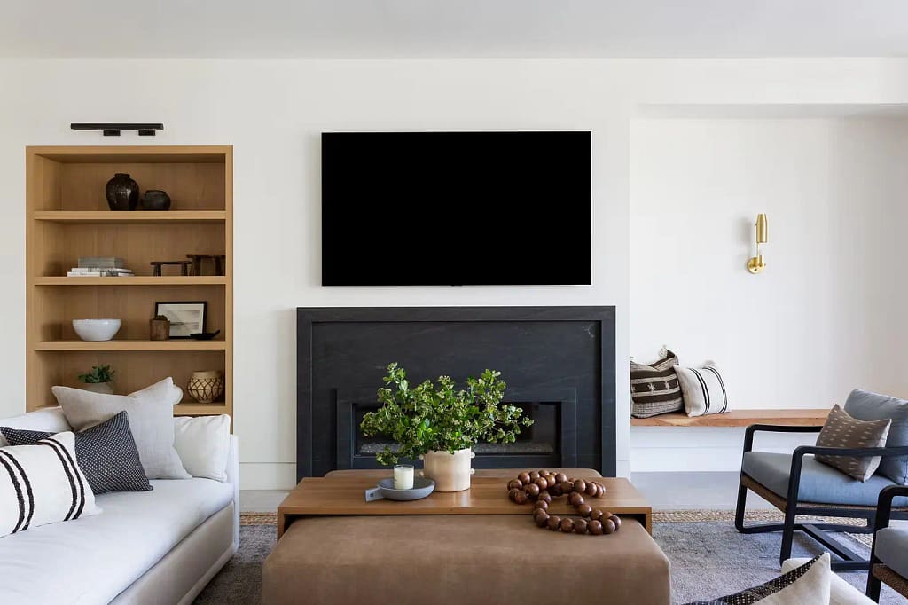 Modern home renovation in Edgemont Village by Quay Construction featuring minimalist oak wall paneling and a custom black fireplace surround.