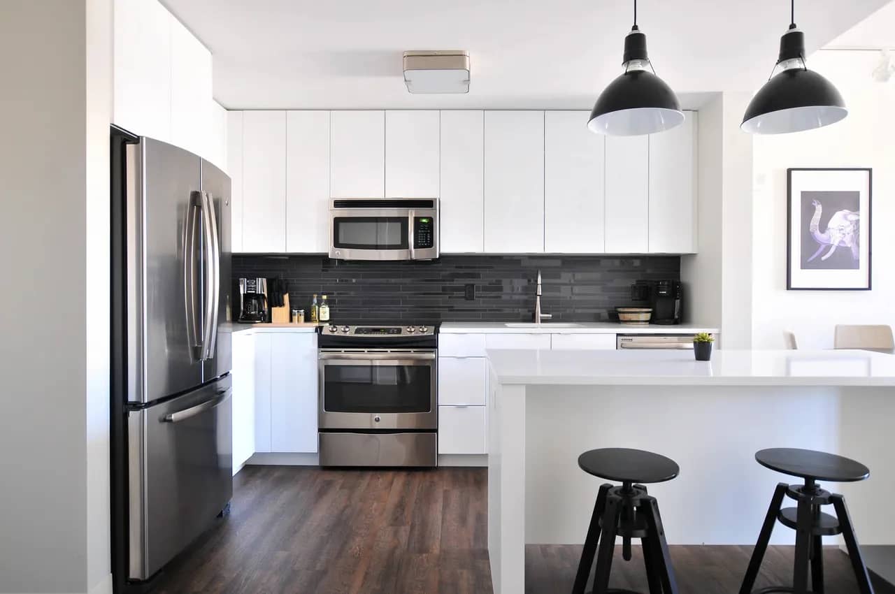 a kitchen with white cabinets and black bar stools