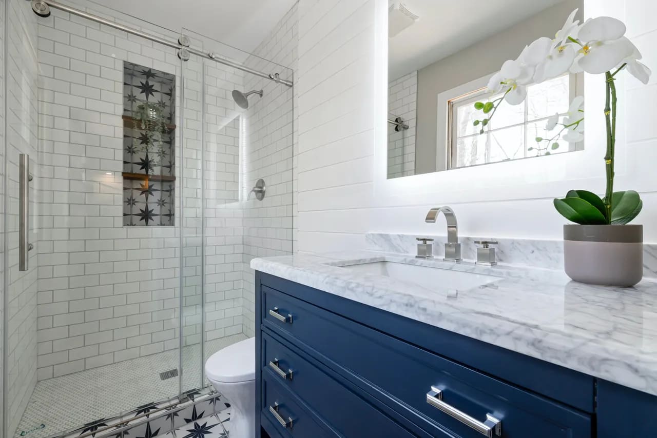Blue bathroom vanity with quartz countertops and walk-in shower