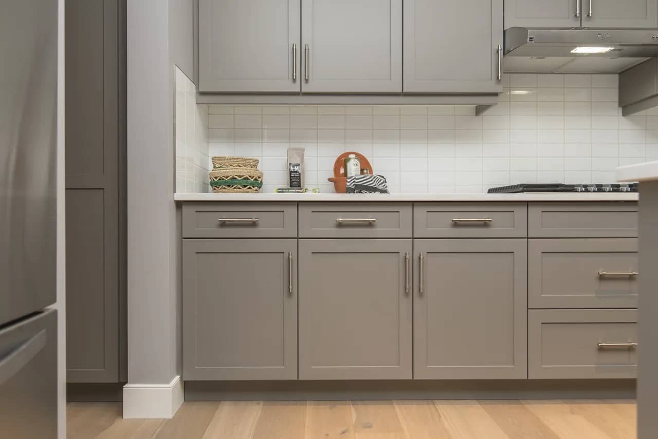Grey kitchen cabinets with white subway tile backsplash.