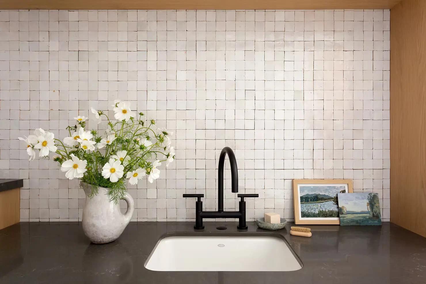 A modern basement renovation in West Vancouver featuring a dark countertop, minimalist black faucet, and white square tile backsplash installed by a professional contractor.
