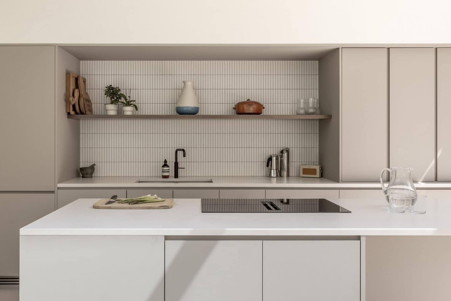 High-end kitchen renovation in Deer Lake by Quay Construction featuring a marble waterfall island, custom white cabinetry, and a unique arched wood pantry door.