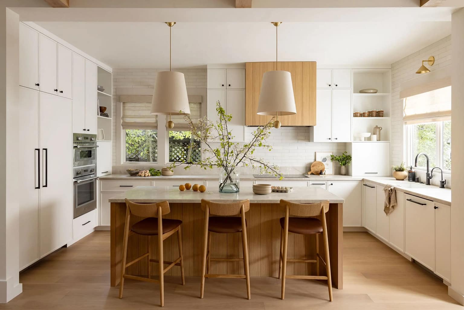 Modern kitchen renovation in Lynn Valley by Quay Construction featuring a marble slab backsplash, white cabinetry, and a custom oak-accented kitchen island.