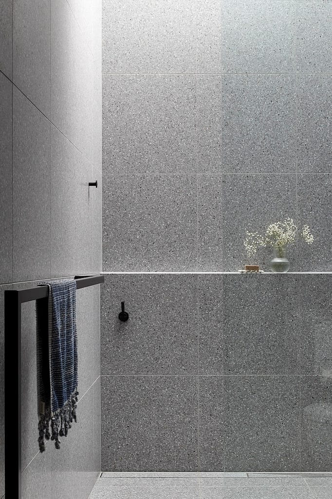Modern bathroom renovation in West Vancouver featuring grey terrazzo wall tiles, matte black hardware, and a built-in shower ledge.