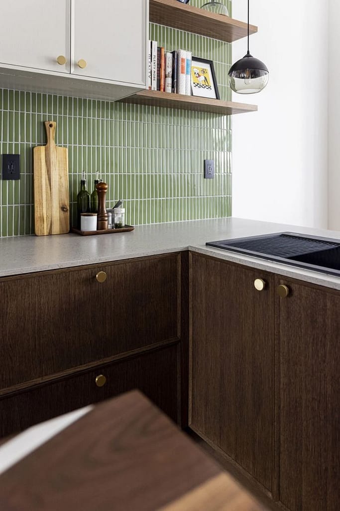 Modern corner kitchen renovation in Coquitlam featuring dark wood base cabinets, a striking green vertical tile backsplash, and custom floating shelves, demonstrating a higher-end cost design.