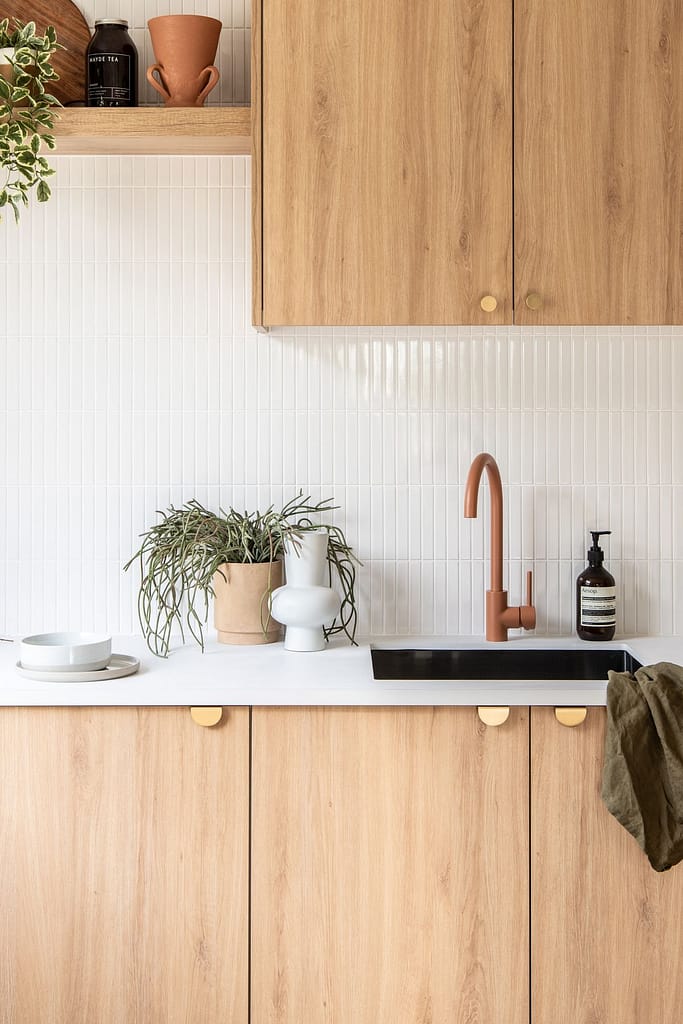 Modern kitchen renovation in Coquitlam featuring flat-panel wood base cabinets, white upper cabinets, and a peninsula with seating, representing a mid-range cost project.