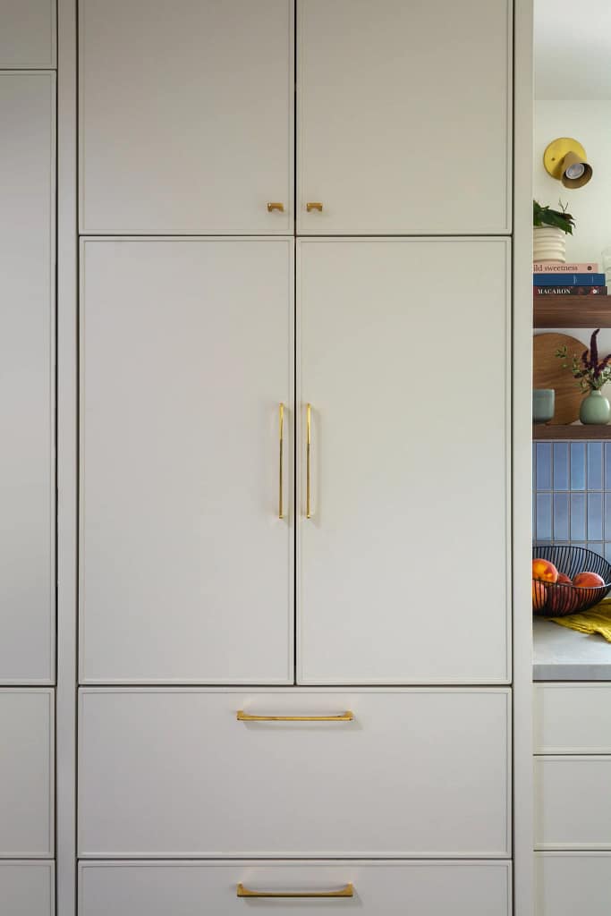 Modern white kitchen cabinets with brass hardware and black frame details in North Vancouver renovation by Quay Construction