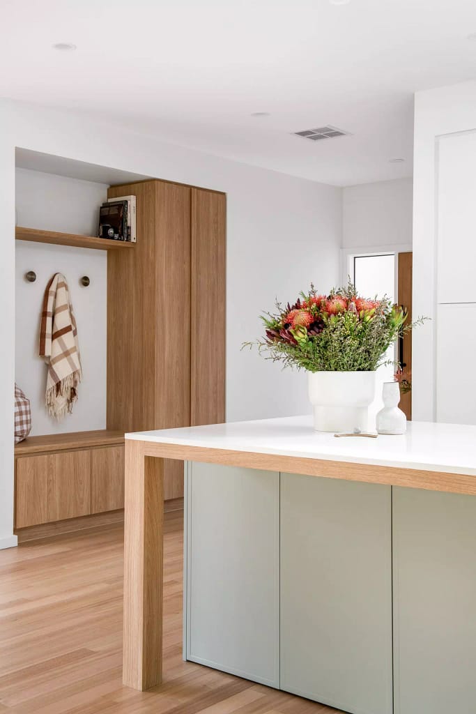 Modern North Vancouver home renovation featuring white quartz waterfall island, white oak cabinetry, and custom built-in storage bench