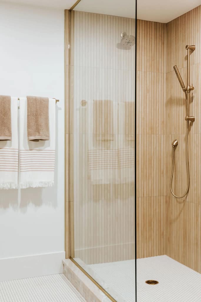 Modern walk-in shower with vertical tile and brass fixtures from North Vancouver bathroom renovation