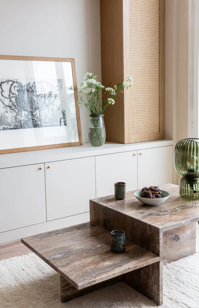 Modern living room from a home renovation in West Point Grey featuring custom white cabinetry with gold hardware and a tall oak cabinet with a woven cane door.