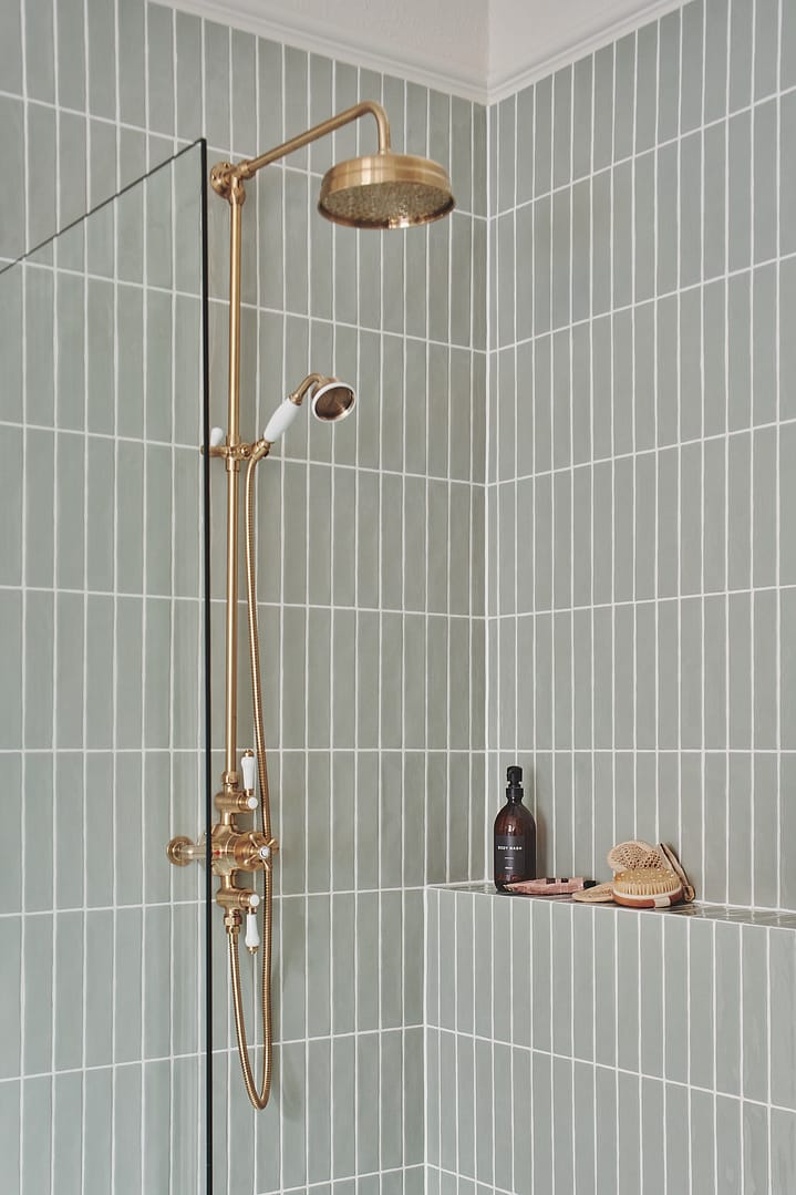 Luxury bathroom from a home renovation in South Cambie featuring sage green vertical stack bond tiles and premium brushed gold shower fixtures with a rain shower head.