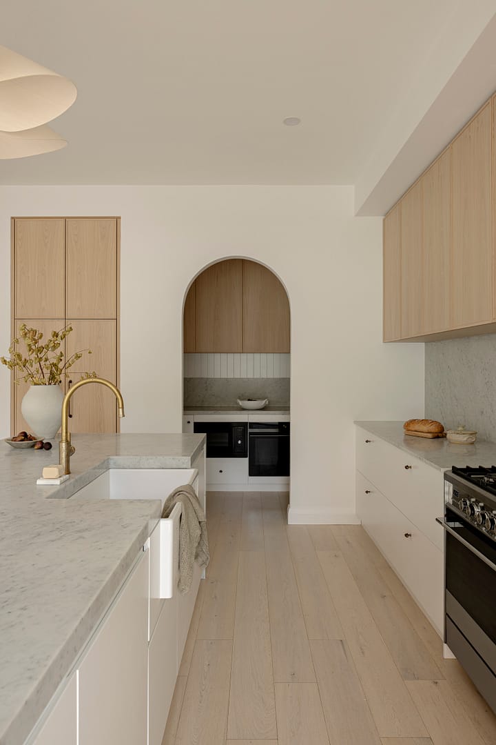 Modern classic Austin Heights kitchen renovation with natural oak cabinets, arched niche, marble countertops, and brass fixtures by QUAY Construction Coquitlam