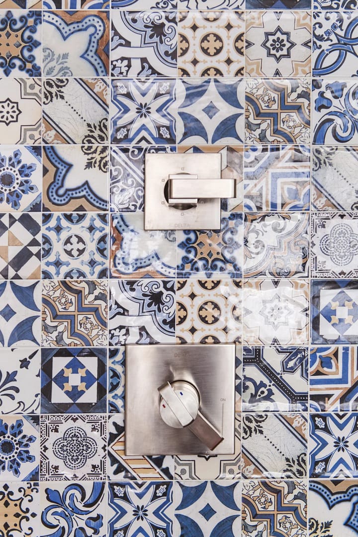 Luxury shower renovation in Mount Pleasant featuring blue and white patterned Mediterranean-style tiles with brushed nickel Delta fixtures.