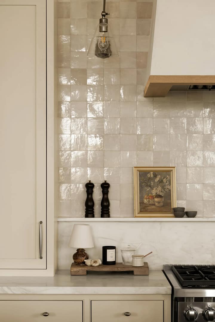 A luxury kitchen from a home renovation in Shaughnessy featuring a glossy cream zellige tile backsplash, marble countertops, and custom cream cabinetry.
