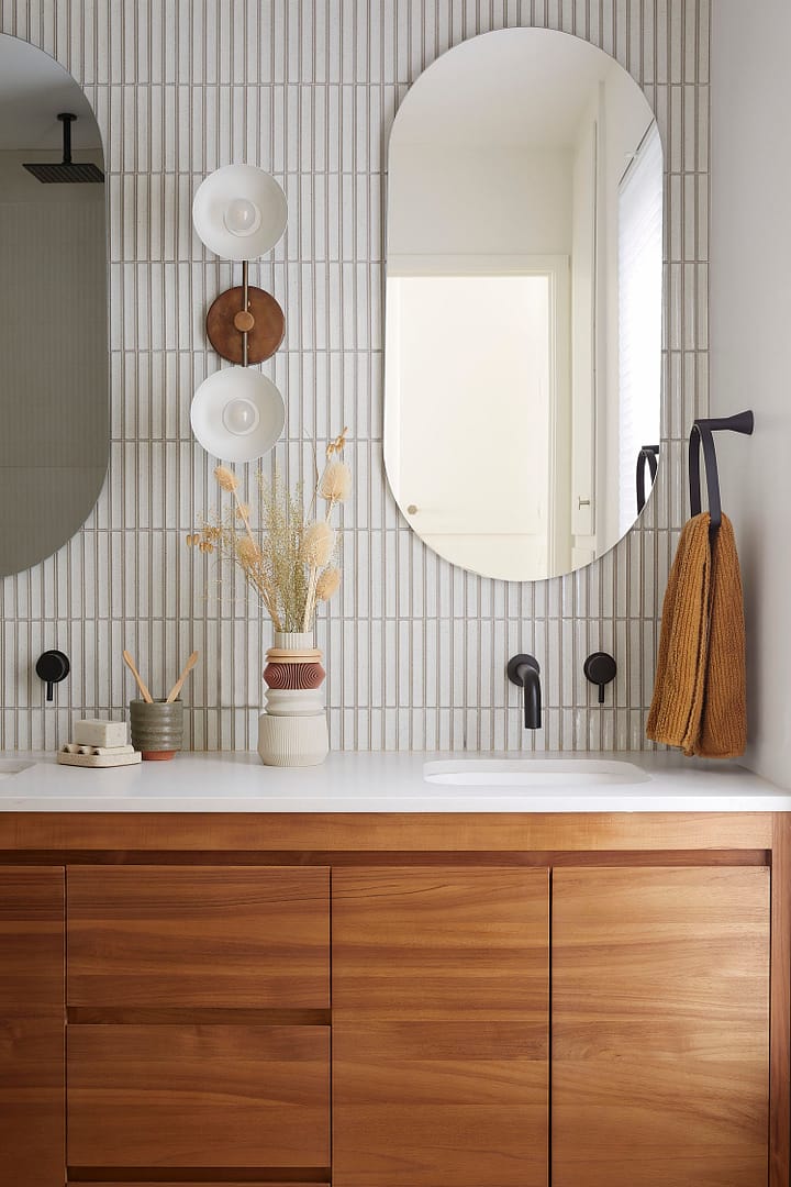Luxury bathroom renovation in West Vancouver featuring a custom walnut double vanity, white kit-kat tile backsplash, and matte black wall-mounted faucets.