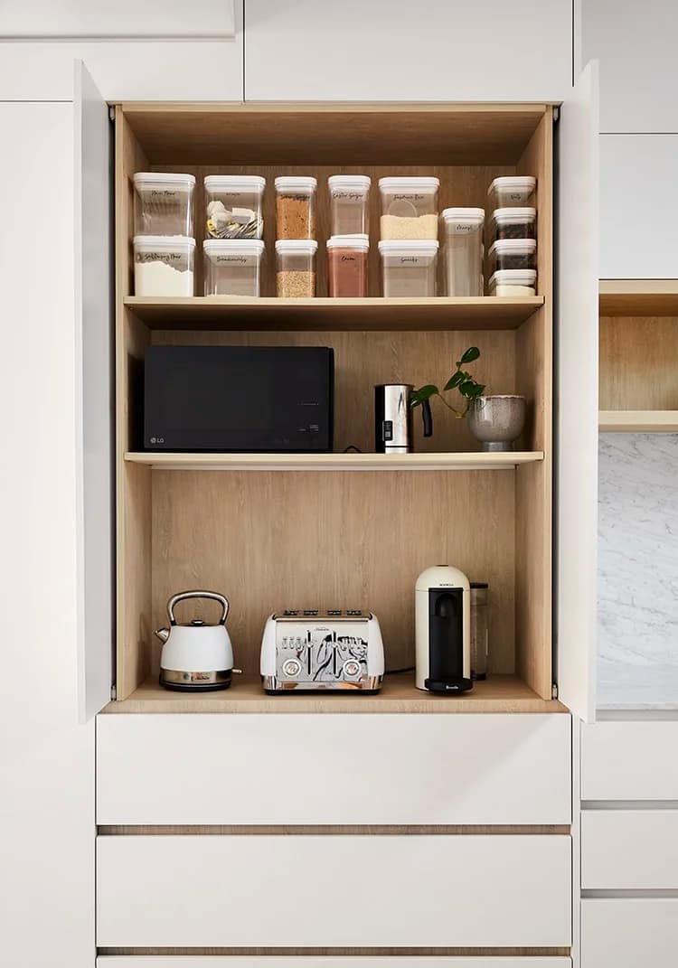 Modern kitchen pantry from a home renovation in Kensington-Cedar Cottage featuring white pocket doors, oak shelving, and organized glass containers with countertop appliances.