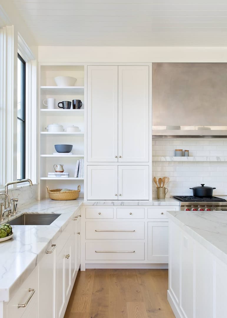 Classic Burke Mountain white kitchen renovation with marble countertops, subway tile backsplash, open shelving, and polished nickel hardware on shaker cabinets