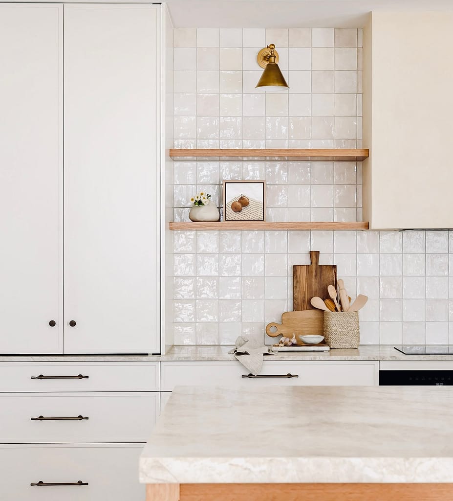Luxury home renovation in Kitsilano by Quay Construction featuring a modern kitchen with a large waterfall island, minimalist white cabinetry, and gold pendant lighting.