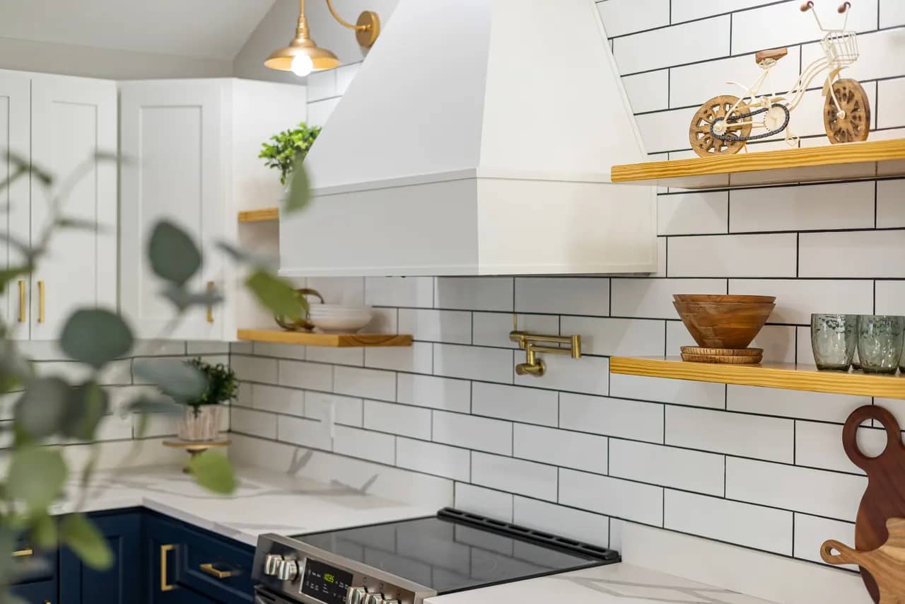 two tone navy and white kitchen with subway tiled backsplashes and gold fixtures