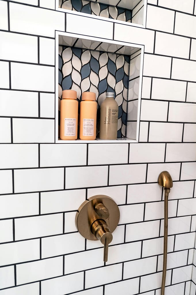 Modern bathroom shower with brass fixtures and geometric tiles in New York.