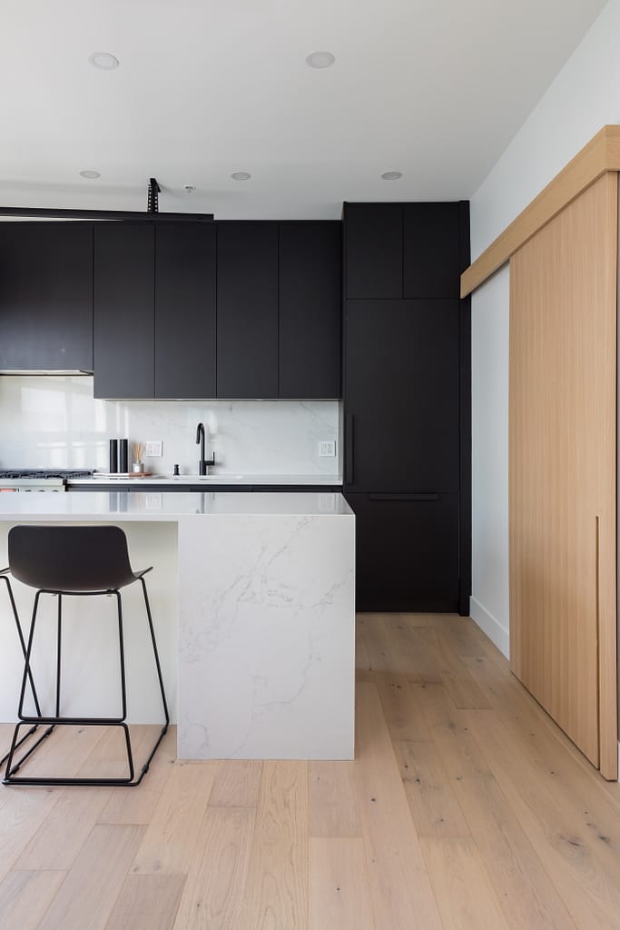 condo kitchen with black cabinets and oak hardwood flooring