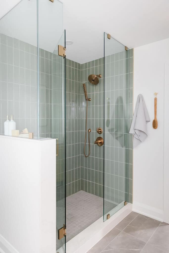shower with green subway tiles and gold shower head